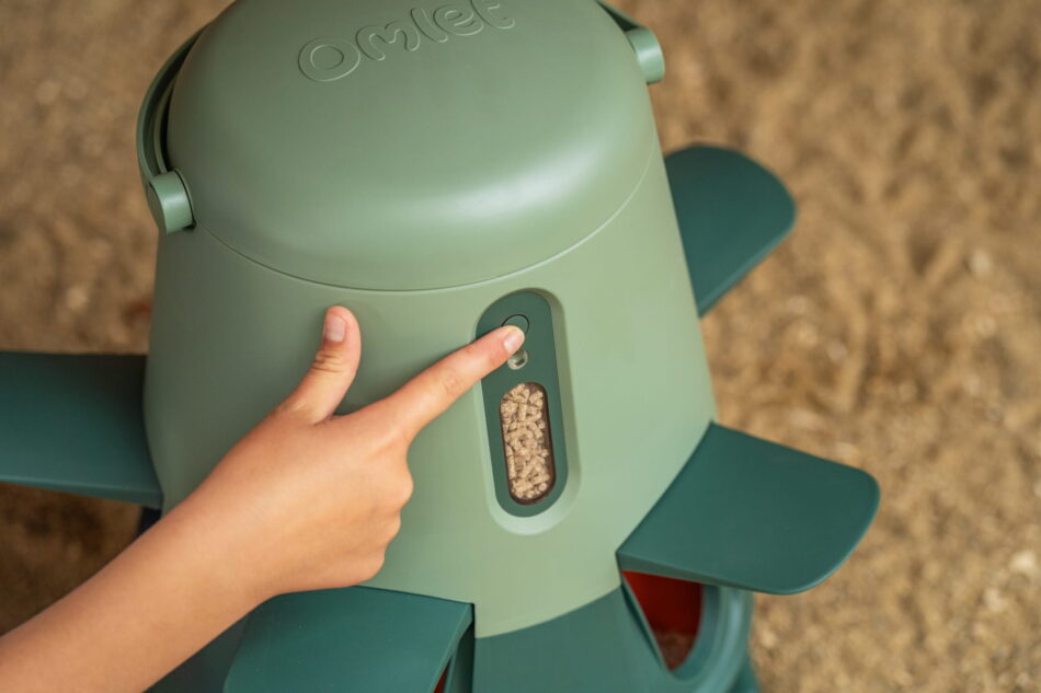 Ein Mädchen drückt den Knopf eines Intelligenten Futterautomaten von Omlet