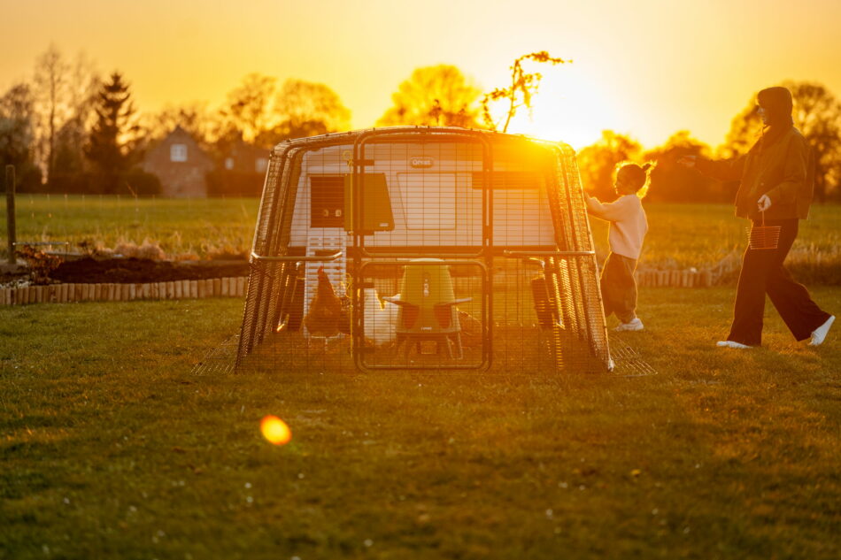 Mutter und Tochter gehen bei Sonnenuntergang zum Eglu Pro