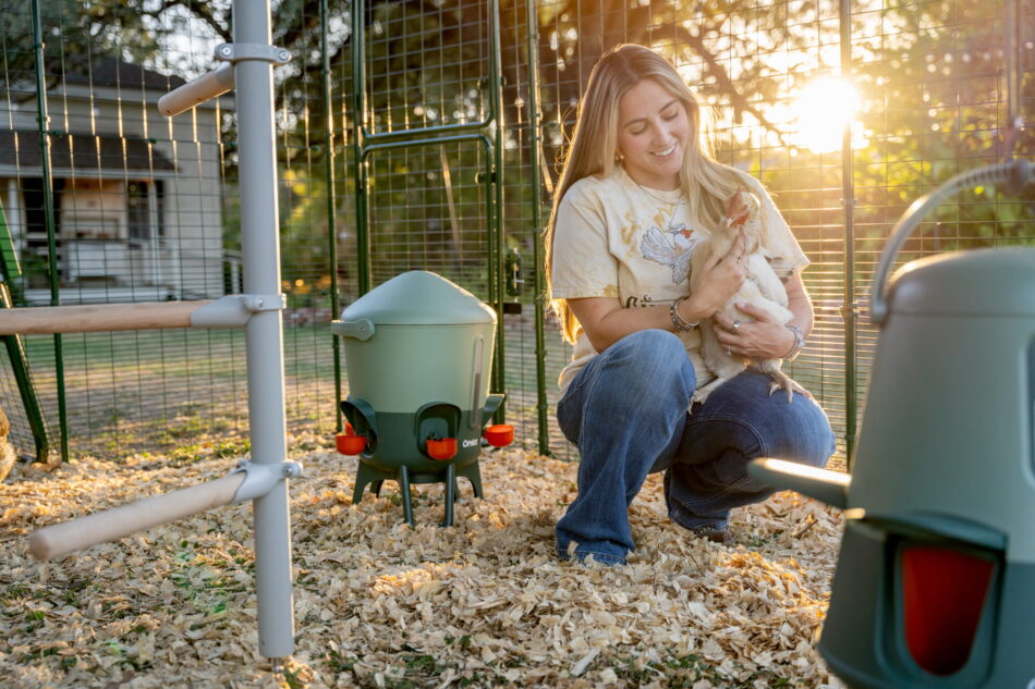 Eine Frau mit einem Huhn auf dem Arm im Omlet Walk In Gehege