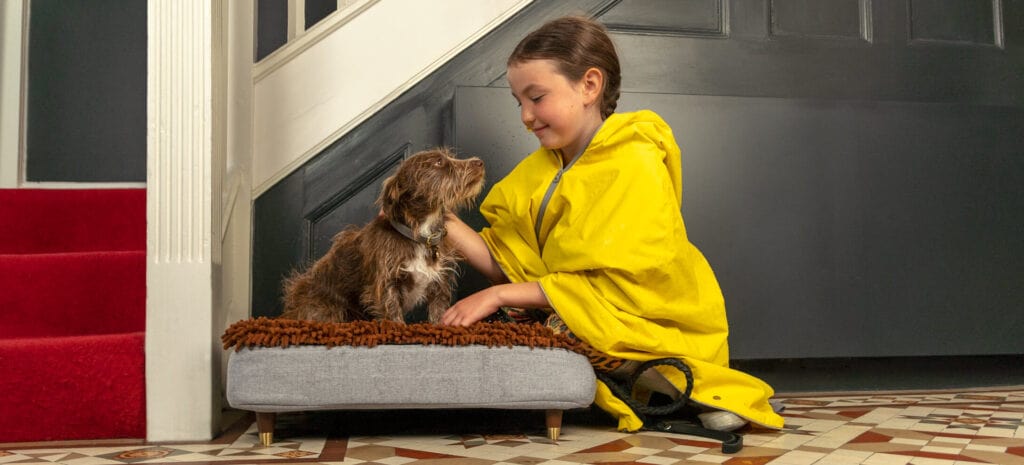 Mädchen streichelt einen braunen Hund auf dem Topology Hundebett mit Mikrofaser Topper