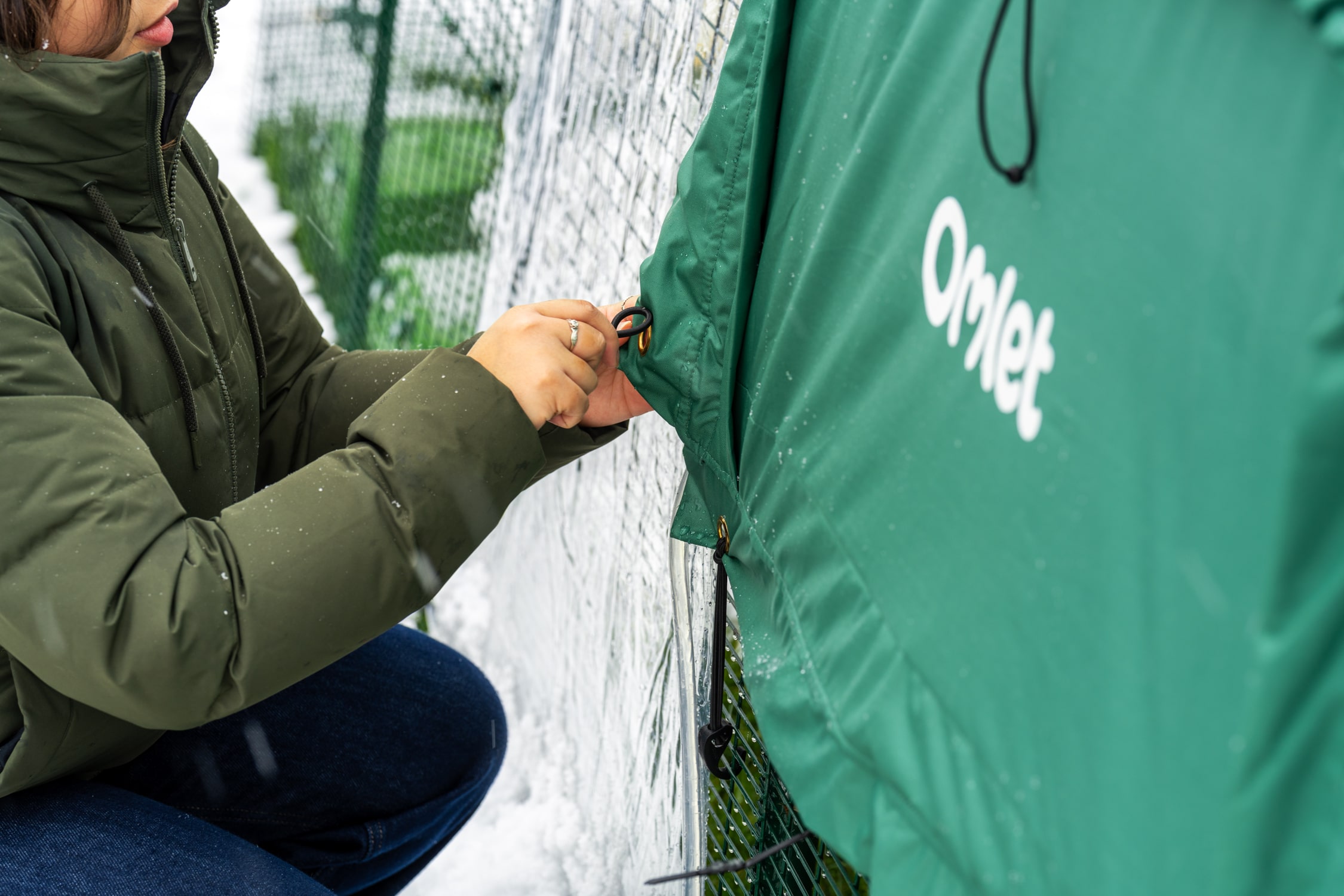 Eine Frau bringt den Anti Frostüberzug am Eglu Pro an