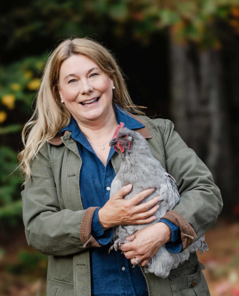Eine lächelnde Frau mit ihrem Huhn auf dem Arm