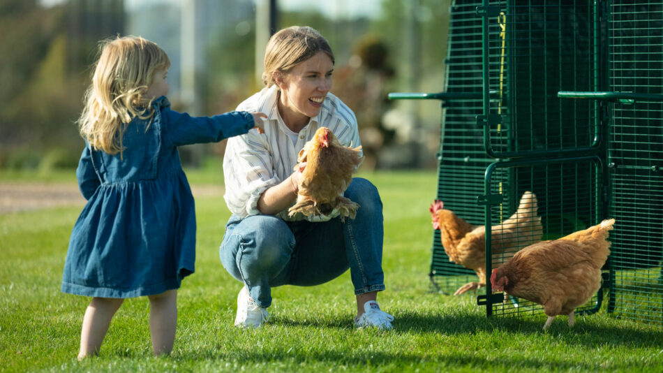 Eine Frau und ein Mädchen mit Hühnern vorm Eglu Pro